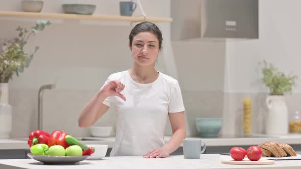 Indian Woman Showing Thumbs Down While Standing in Kitchen alt