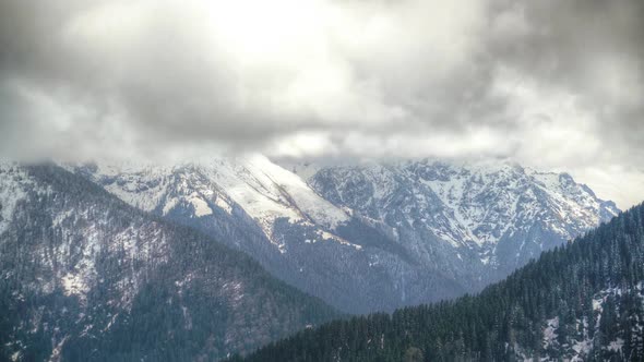 8K Dark Storm Clouds in Pine Forest Covered Valley in Snowy Mountains