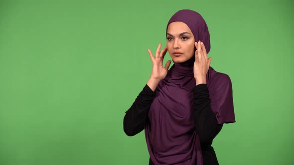 A Young Beautiful Muslim Woman Adjusts Her Clothes and Smiles at the Camera Green Screen Background