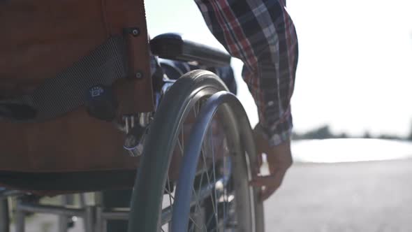 A Man in a Wheelchair Walks on the Waterfront