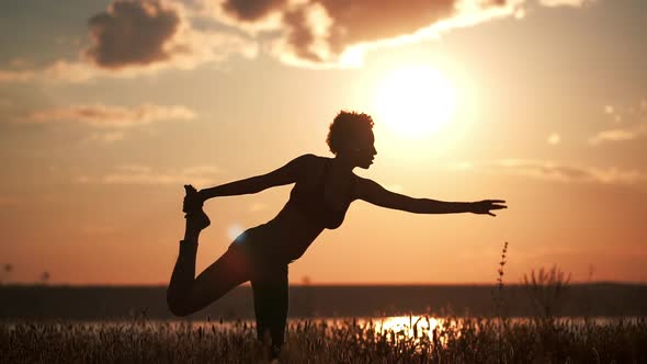 Silhouette of Young Beautiful Girl Practicing Yoga at Sunset alt
