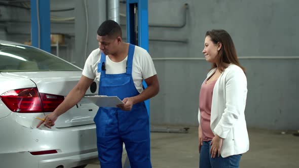 Mechanic Shows Car Damage To a Woman