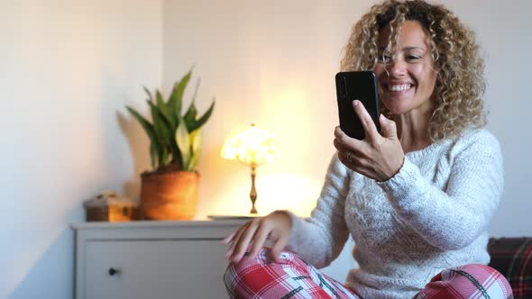 Woman making video call through smartphone sitting on bed