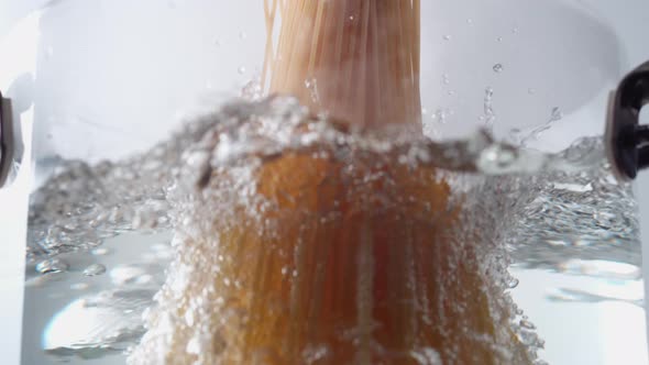 Camera follows cooking spaghetti noodles in boiling water. Slow Motion. alt
