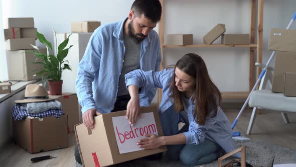 Young Couple Prepare Personal Stuff Relocating to First Own House Sealing Cardboard Boxes with alt