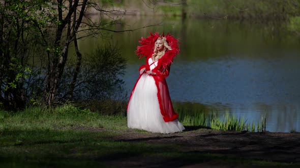 Sexy Blonde Woman is Wearing Extravagant Mediaeval Dress is Posing on Shore of River in Forest alt