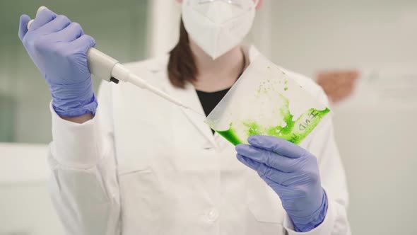 Medical Researcher Using Pipettor To Measure The Green Liquid. close up alt