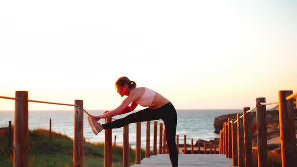 Flexible Caucasian Girl Stretches Legs After an Intensive Running Workout alt