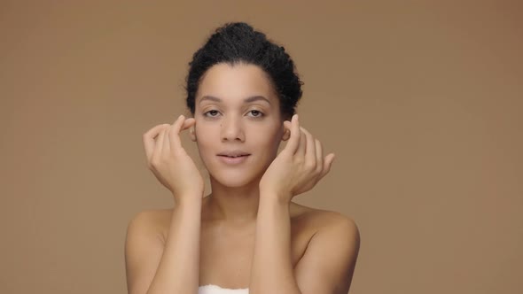 Beauty Portrait of Young African American Woman Striking Face with Fingers and Giving Gentle Skin alt