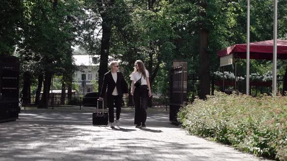 Young Couple Man and Woman Walking Street in Summer Rolling Suitcase on Wheels alt