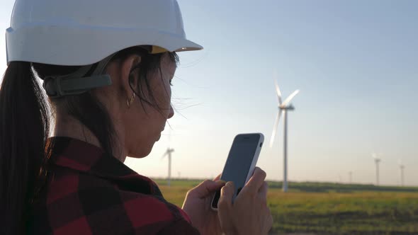 Woman Engineer Working in Wind Turbine Electricity Industrial at Sunset. alt