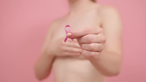 Close Up, Woman Holding Silk Pink Ribbon Between Her Fingers. Breast Cancer Awareness Month Pink alt