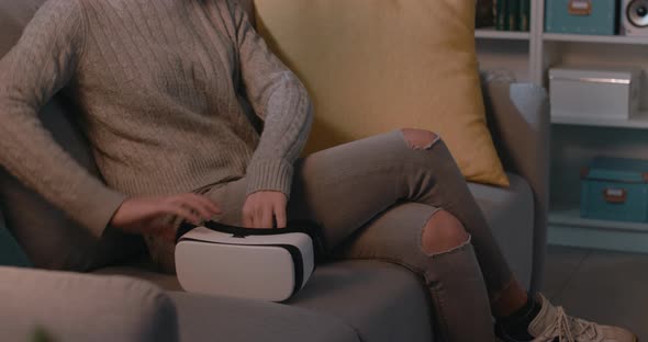 Young woman sitting on the couch and accessing VR