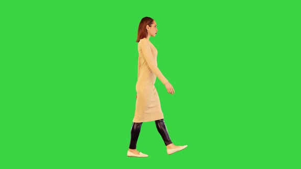 Robotic Girl in Beige Dress Walks Looking Straght Ahead on a Green Screen Chroma Key