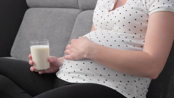 Pregnant Woman on Sofa with Glass of Milk