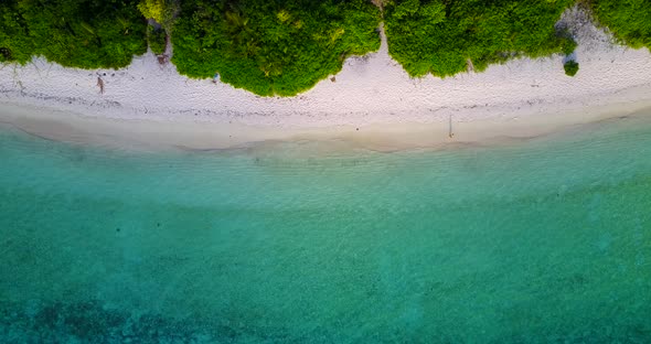 Wide flying copy space shot of a sandy white paradise beach and blue water background  alt