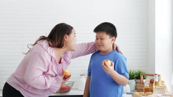Overweight mom and son eating a fresh apple, organic nutrition, vitamin C, diet
