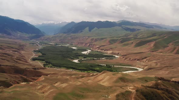 Mountain peaks and grassland under white clouds alt