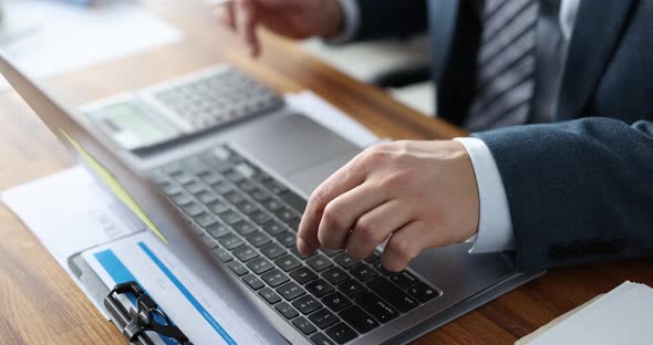 Businessman Use Laptop and Calculators While Sitting at Office Table alt