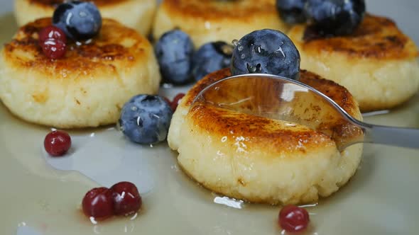 a Spoon Breaks Off a Piece of Curd Cheesecake with Honey and Berries in a Bowl