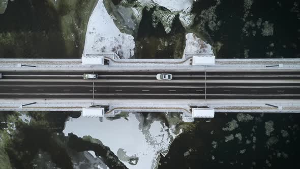 Aerial Top Down View Of Cars Driving On Bridge Over River In Winter