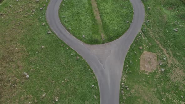 Top down birdseye aerial tracking over a an isolated country roundabout that has only two exits. alt