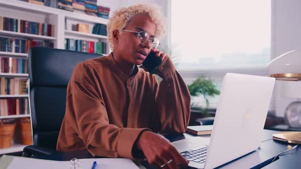 African Woman Employee in Glasses Working in Office Talking on Cellphone alt