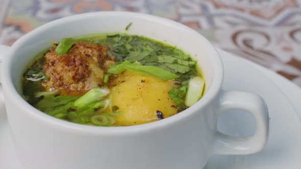 Chicken Soup with Potato and Herbs Spinning Round on Table