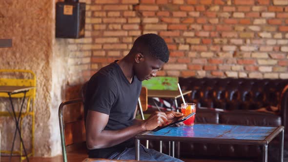 technology, youth - black man at pub scrolls the keyboard of the tablet alt