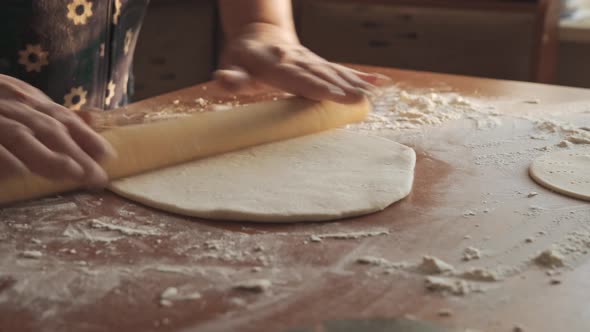 Women's Hands Using a Rolling Pin Roll Out the Dough for Baking