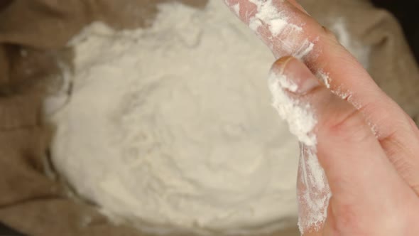 Human holds a handful of a wheat powder by and throws it in a sac