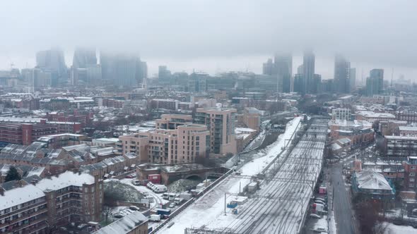 Dolly back aerial drone shot of Snow covering Central London and train tracks alt