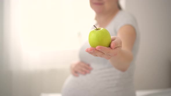 Pregnant Woman is Holding an Apple in Her Hand