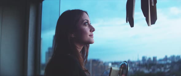 Woman photographer looking outside the balcony and taking a picture alt