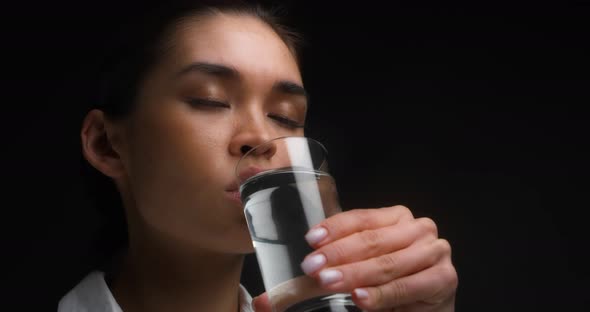Business Woman Takes a Sip of Water From a Clear Glass and Opens Her Eyes