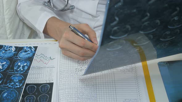 Female Doctor Analyzing Brain Scan And Making Notes