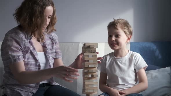 Mother and Son is Playing in Board Game with Wooden Tower Together at Home