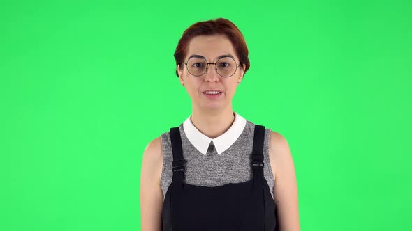 Portrait of Funny Girl in Round Glasses Is Laughing While Looking at Camera. Green Screen alt