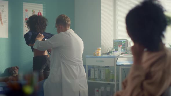 Pediatrician Using Stethoscope Listening Lungs African Girl in Modern Clinic alt