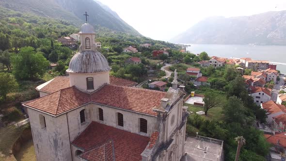 Ancient Church in the Town of Prcanj Against the Backdrop of Greenery and Old Houses alt