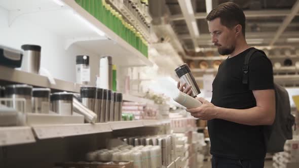 Man Chooses a Thermos at the Shopping Center in Order to Take Him on a Hike alt