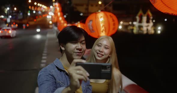 Young Asian couple travel make a video live streaming on social network by smartphone. alt