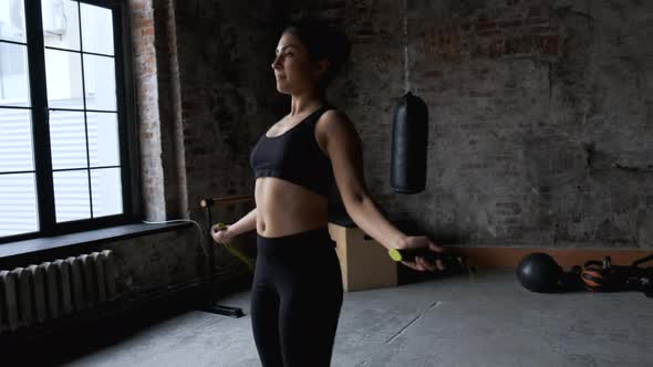 An attractive and athletic girl jumping rope, she is engaged in cardio exercises in gym  alt