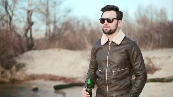 Relaxed Handsome Man Drinking Beer. Cheerful Man Celebrating And Drinking Cold Beer Outdoors. alt