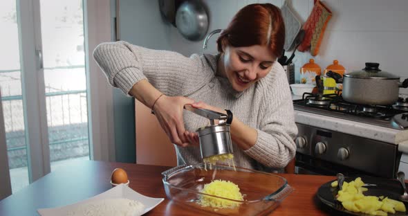 Girl is Mashing Boiled Potatoes for the Preparation of Dumplings and Croquettes alt