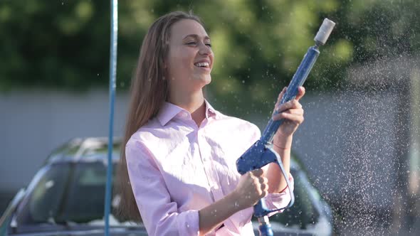Positive Woman Spraying Car Wash Shampoo with High Pressure Washer in Slow Motion Turning Off alt
