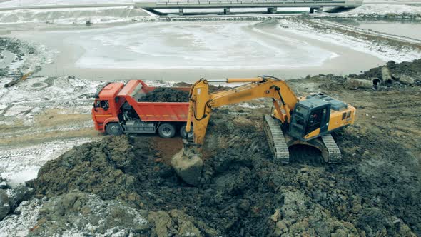 Industrial Tractor Loads a Truck with Sand at a Quarry. New Constructions Site. Heavy Machinery at a alt