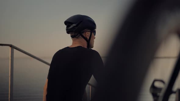 Athlete Relaxing After Hard Cycling Race. Tired Triathlon Cyclist Rest On Nature After Cycling. alt