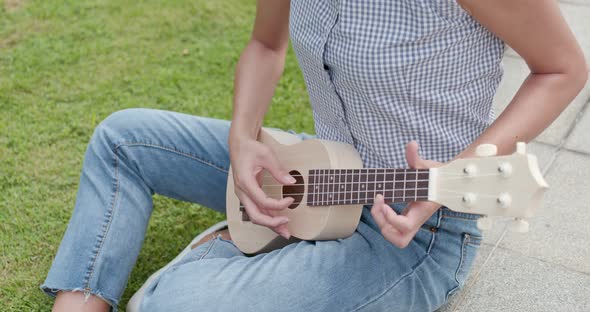 Woman playing ukulele at city alt