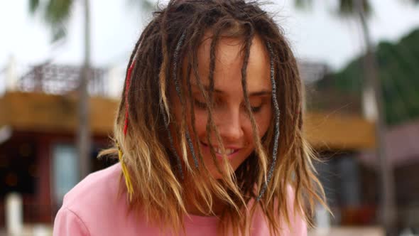 A Woman with Dreadlocks Plays a Musical Instrument and Enjoys Music